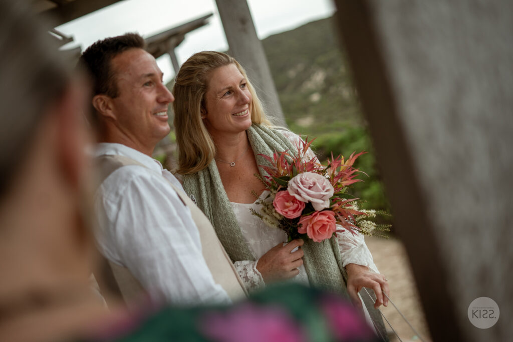A wedding couple smiling towards their celebrant