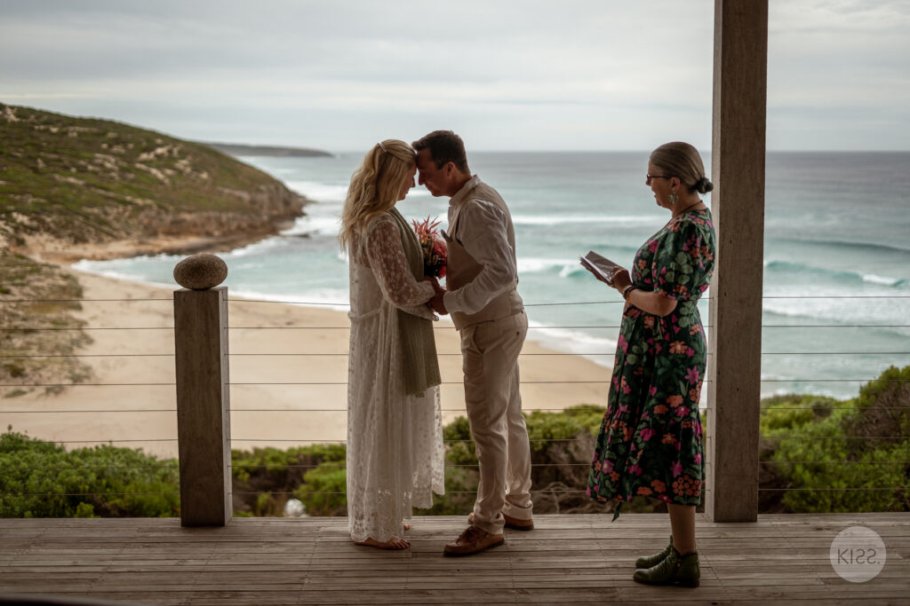 A couple kissing during their ceremony on a coastal deck