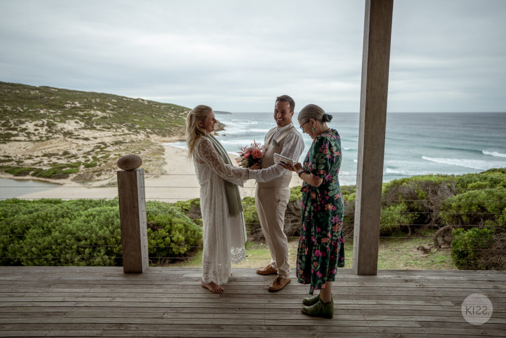A couple and celebrant at an ocean-view deck ceremony