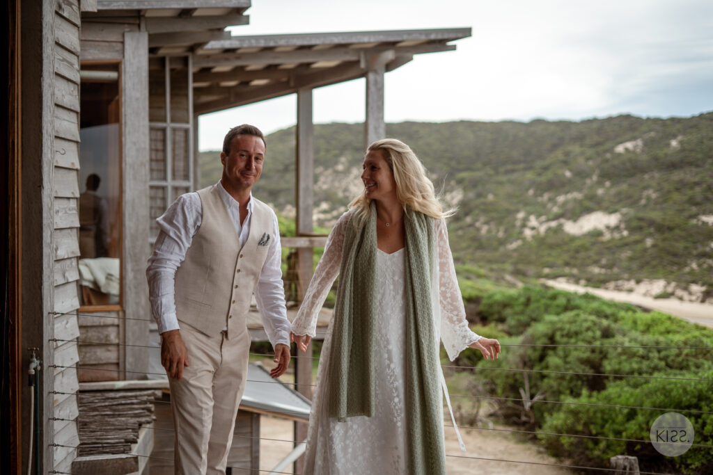 A couple holding hands beside their coastal accommodation