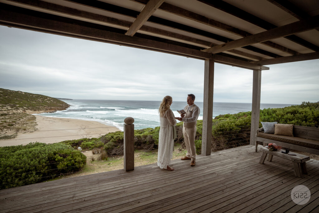 A wedding couple holding hands on an ocean-view deck