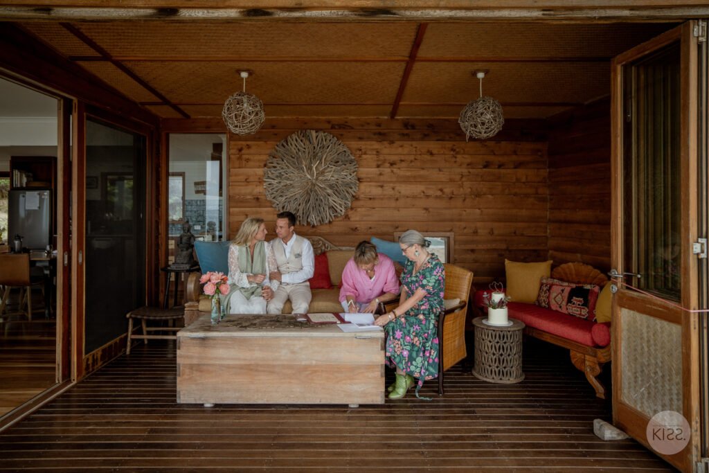 A groom signing the marriage register beside the celebrant indoors