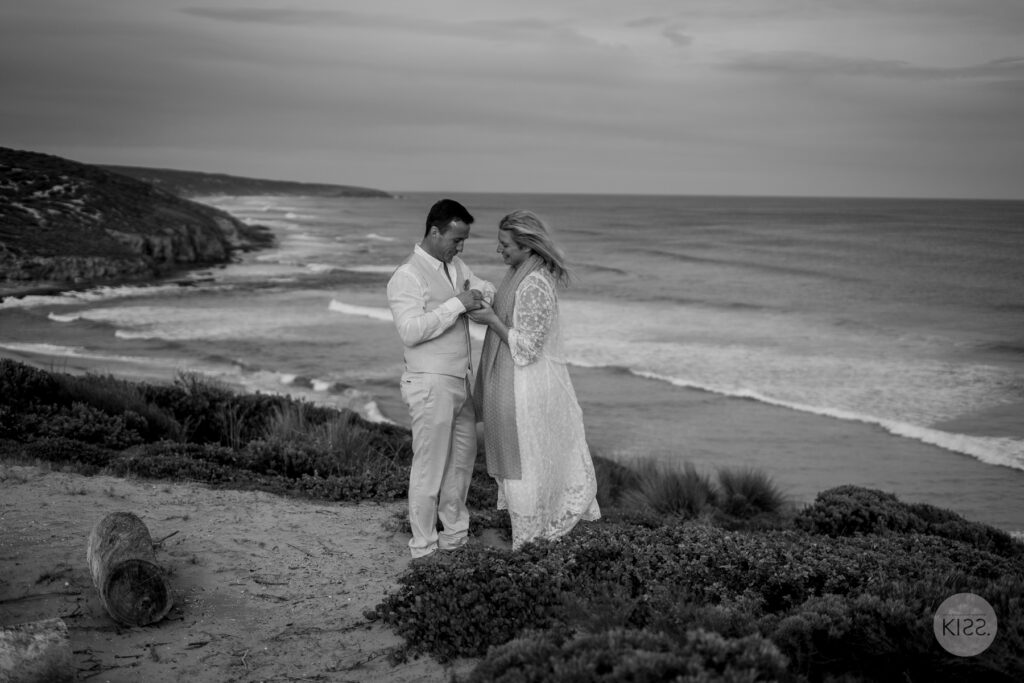A wedding couple standing above the coast in black and white
