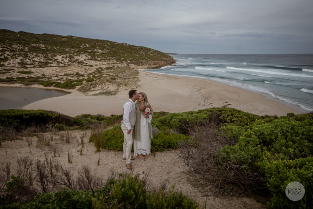 A wedding couple looking at each other above the beach