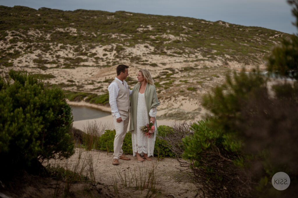 A wedding couple walking among coastal plants