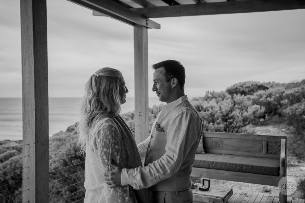 A couple embracing on a covered deck in black and white