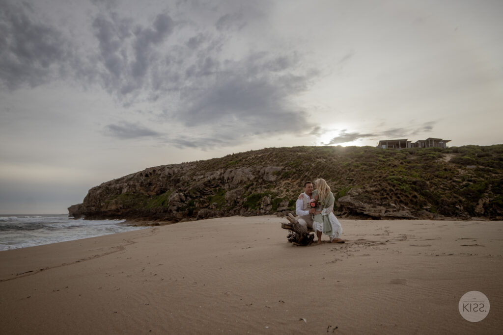 A wedding couple sitting together on a wide beach