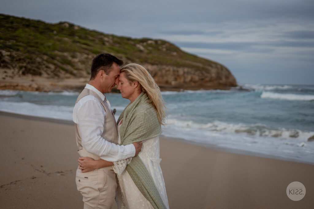 A wedding couple touching foreheads beside the sea