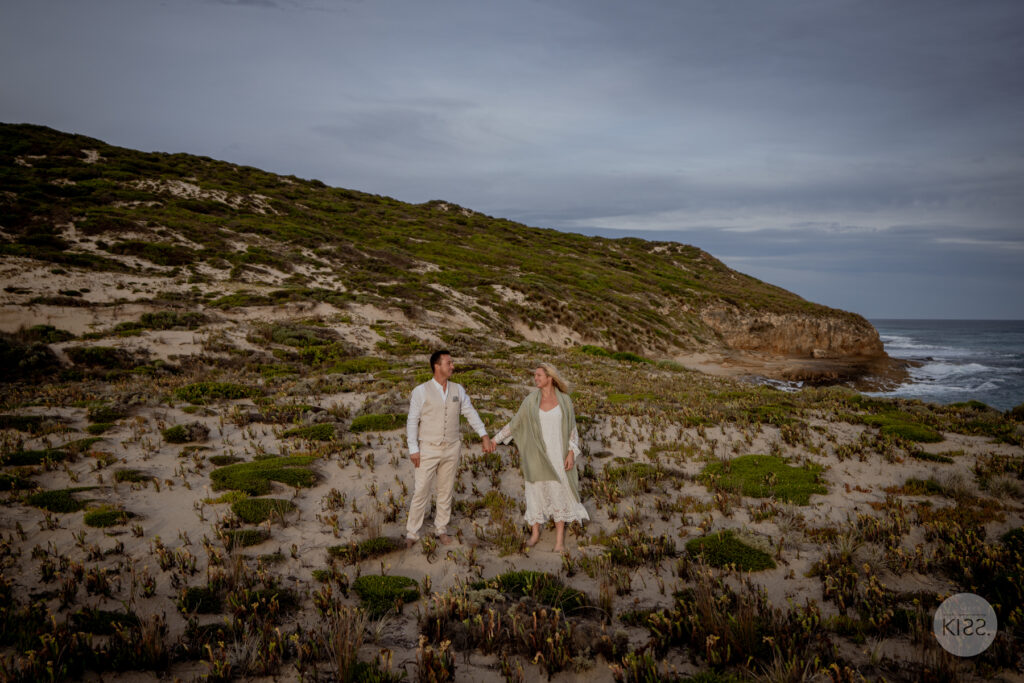 A couple holding hands among coastal vegetation