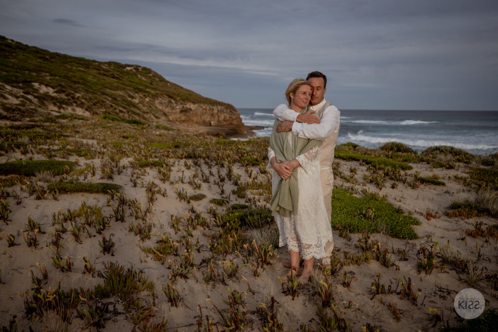 A groom embracing his bride above the beach