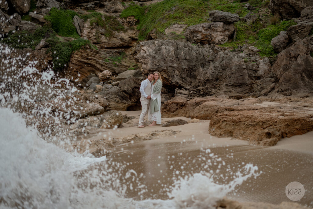 A wedding couple beside coastal rocks and breaking waves