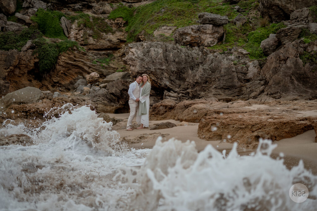 A wedding couple standing beside waves on a Kangaroo Island beach