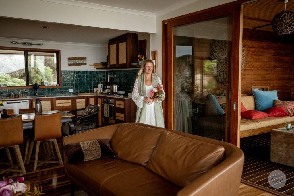 A bride standing inside coastal accommodation before her wedding