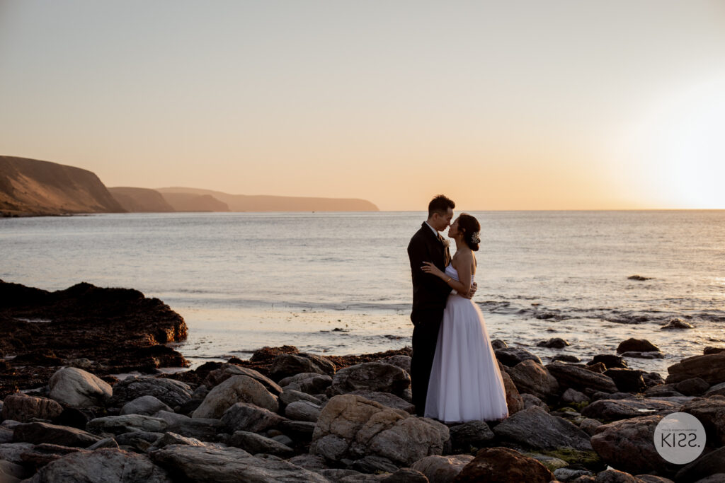 A wedding couple silhouetted beside the sea at dusk