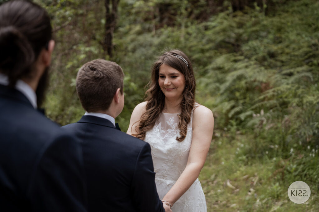 A bride smiling at her groom during their outdoor ceremony