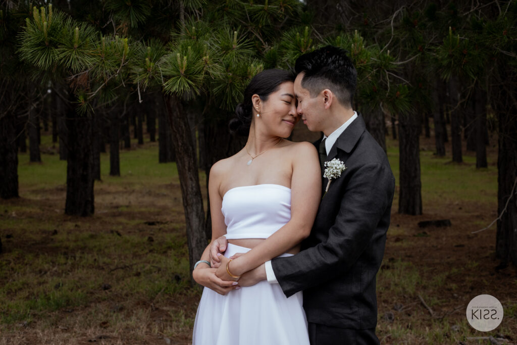 A wedding couple embracing beneath trees