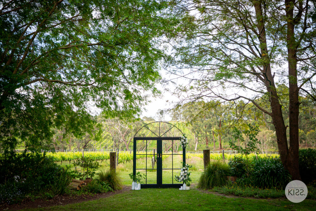 Floral wedding arbour beneath trees in a vineyard setting
