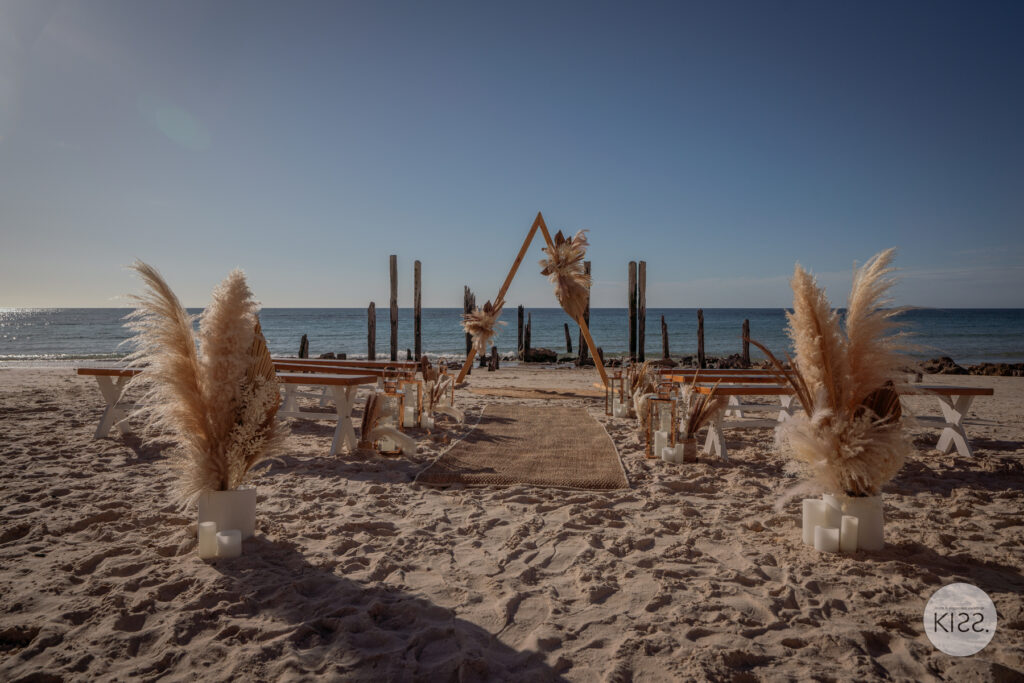 Lanterns and dried flowers lining a beach wedding aisle