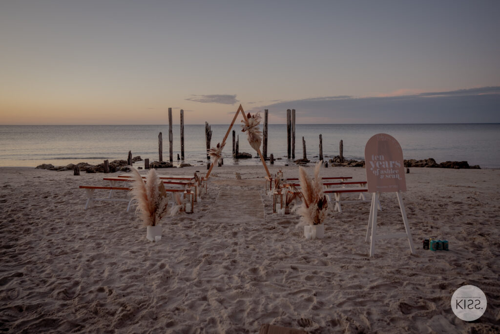 Beach wedding chairs and arbour arranged at sunset