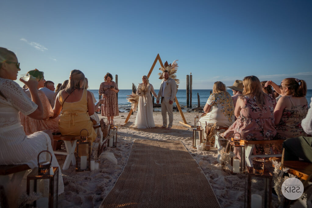 Guests watching a beach wedding ceremony