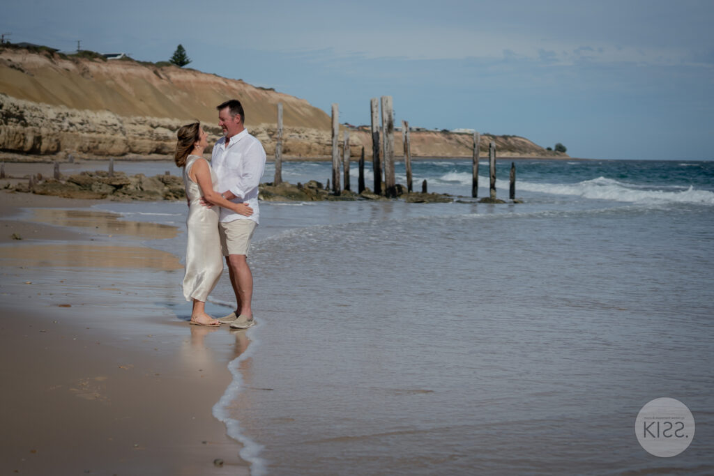 A wedding couple embracing at the water's edge at Port Willunga