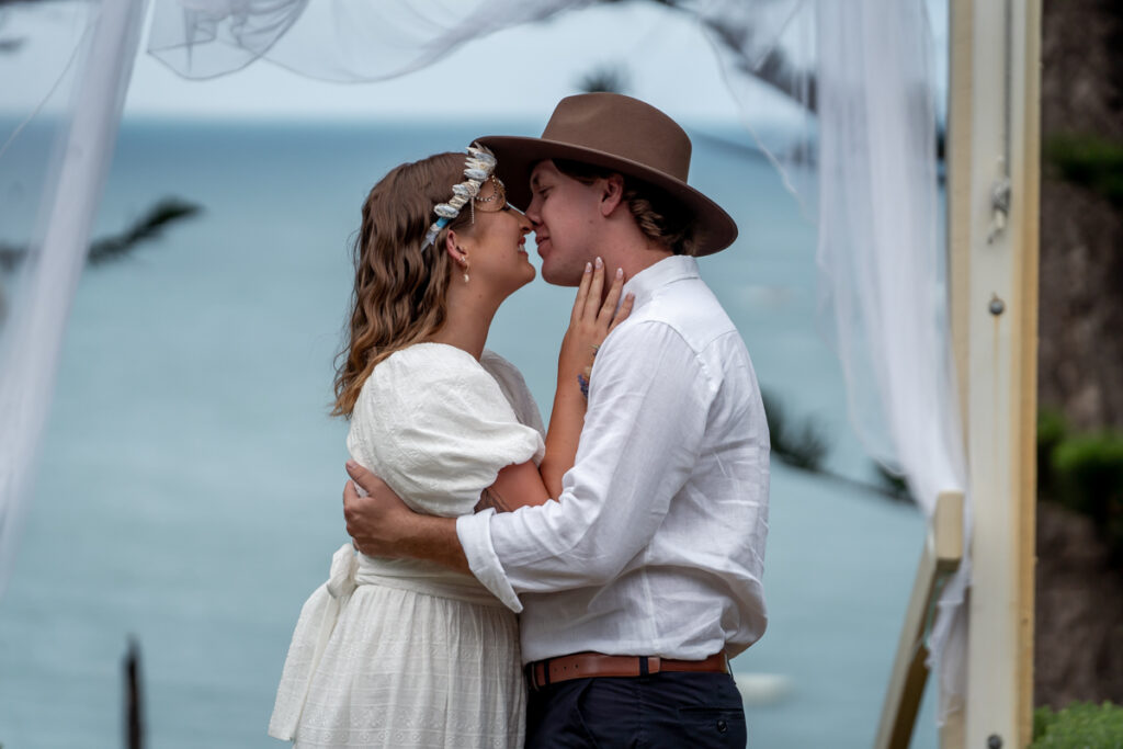 A wedding couple kissing beside a painted wall