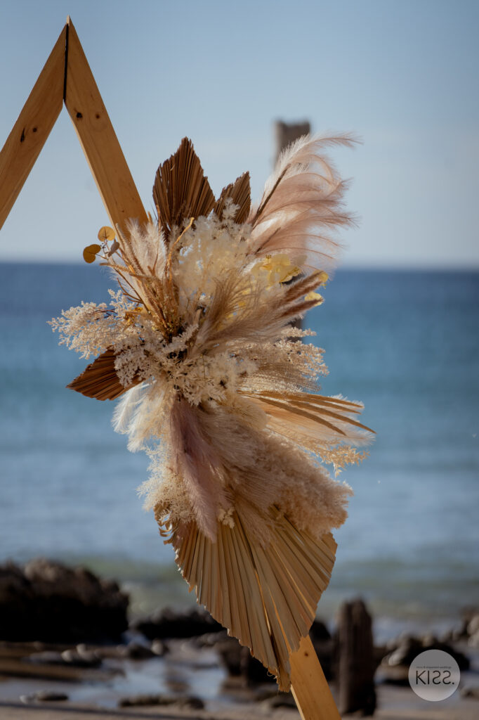 Dried flowers decorating a triangular beach wedding arbour