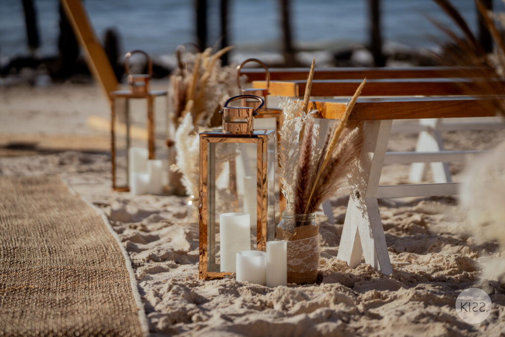 Lanterns, candles and dried flowers decorating a beach ceremony