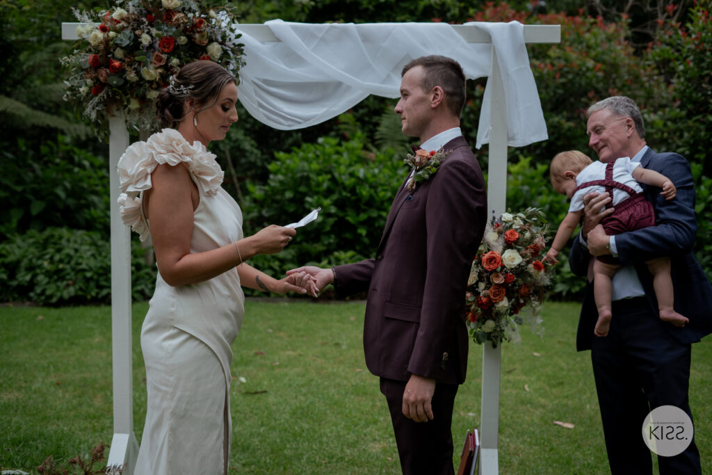 A bride reading her vows while holding her groom's hand