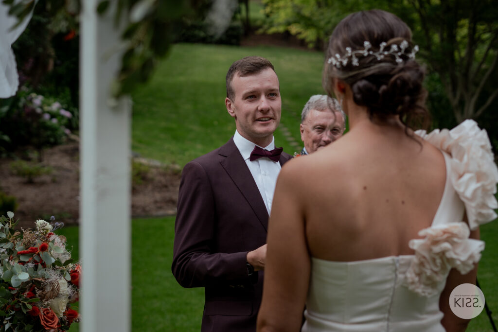 A groom smiling at his bride during their vows