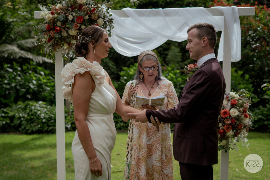 A wedding couple exchanging rings with their celebrant nearby