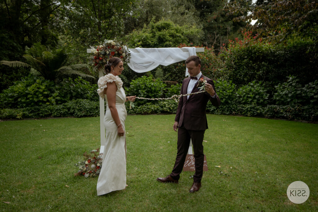 A garden wedding ceremony beneath a floral arbour