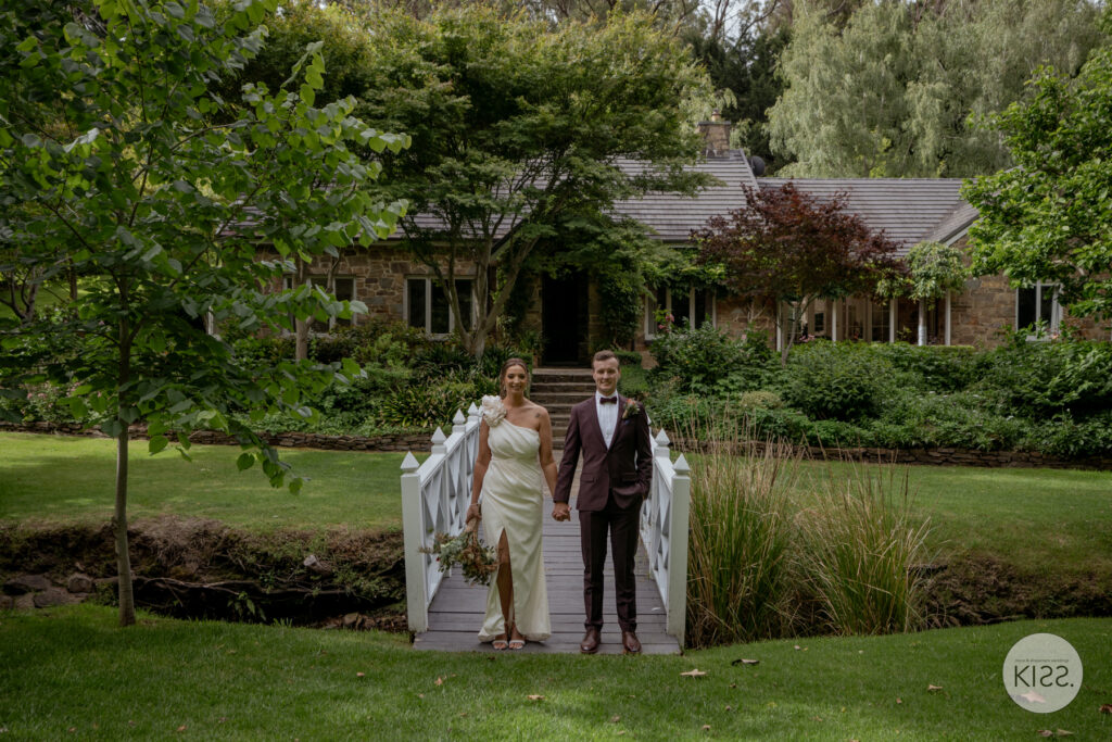 A wedding couple on a white footbridge over a garden pond