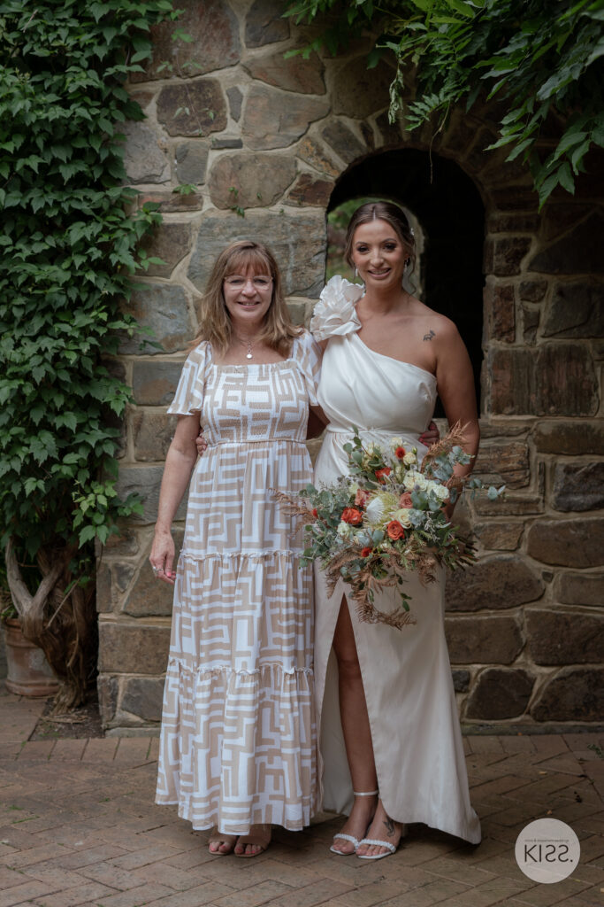 A bride and guest standing beside a stone cottage doorway