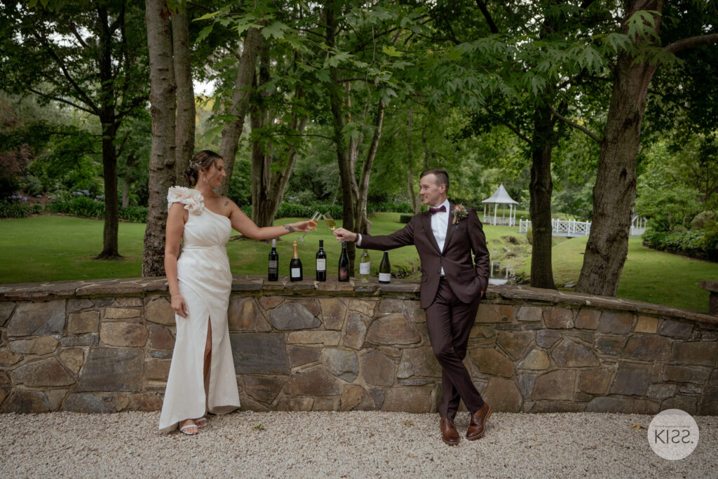 A wedding couple making a toast beside a stone wall