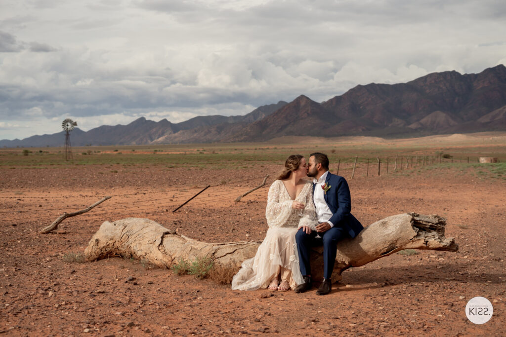 A wedding couple sitting together in an open landscape beneath the Flinders Ranges