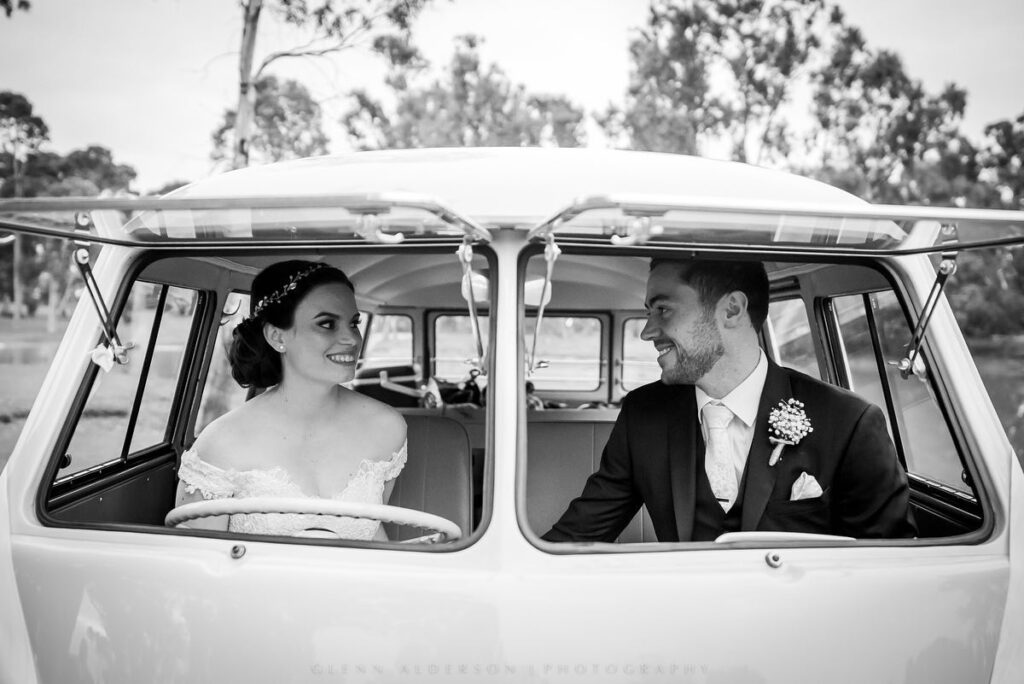 A wedding couple looking at each other inside a vintage vehicle in black and white