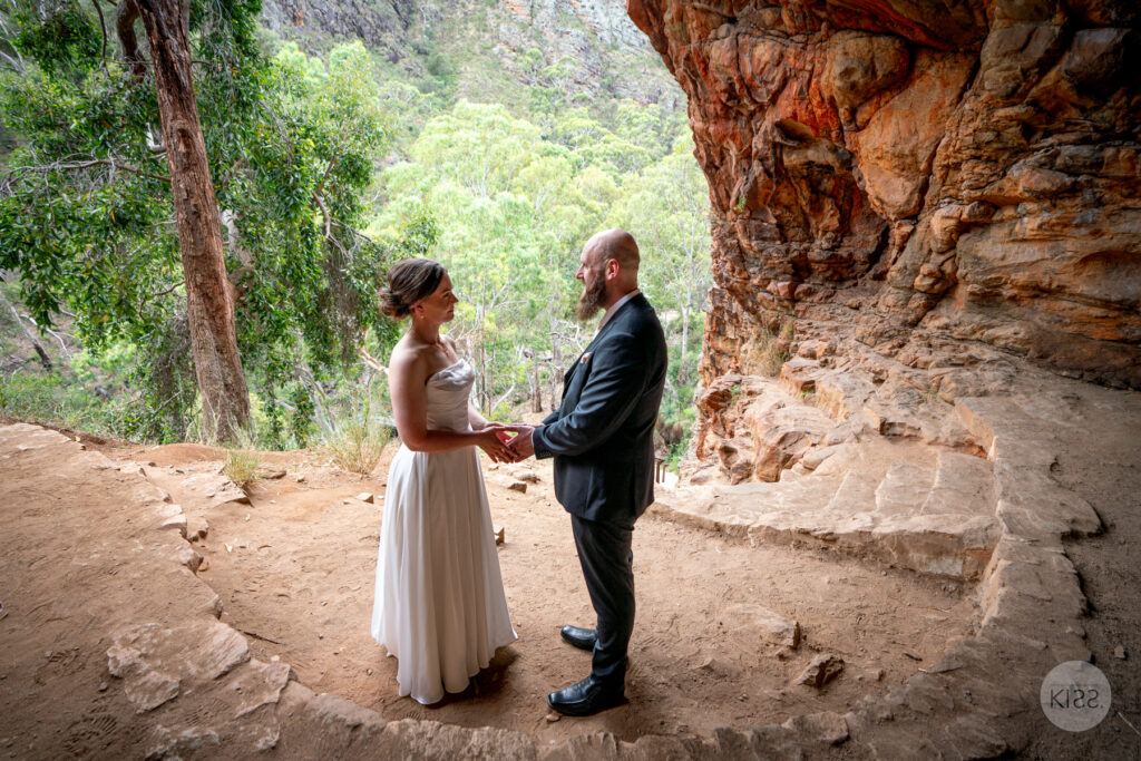 A couple holding hands during their ceremony inside a rocky cave