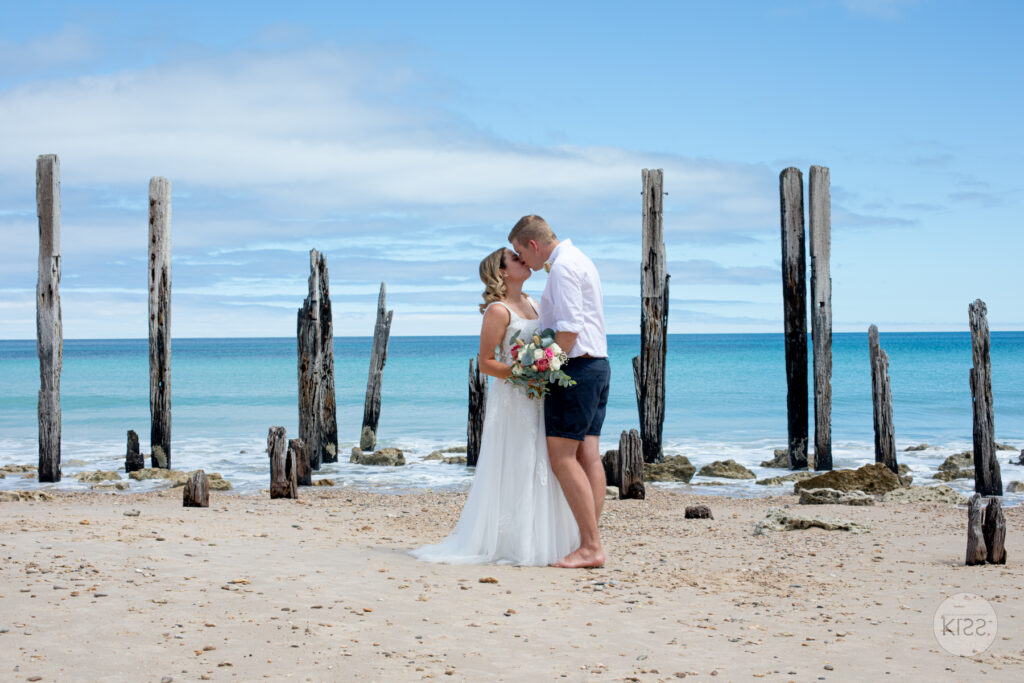 A wedding couple embracing beside old jetty posts at Port Willunga