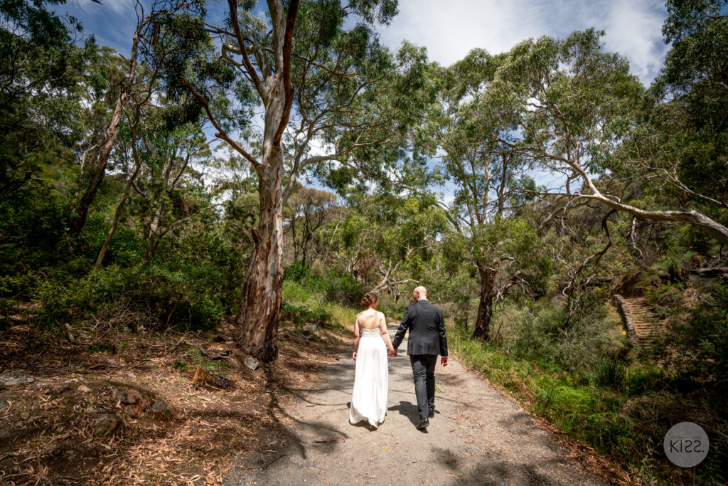 A wedding couple walking along a bushland track