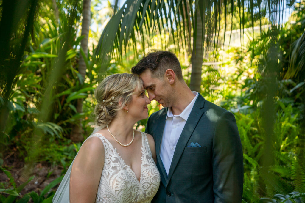 A wedding couple smiling together among tropical plants