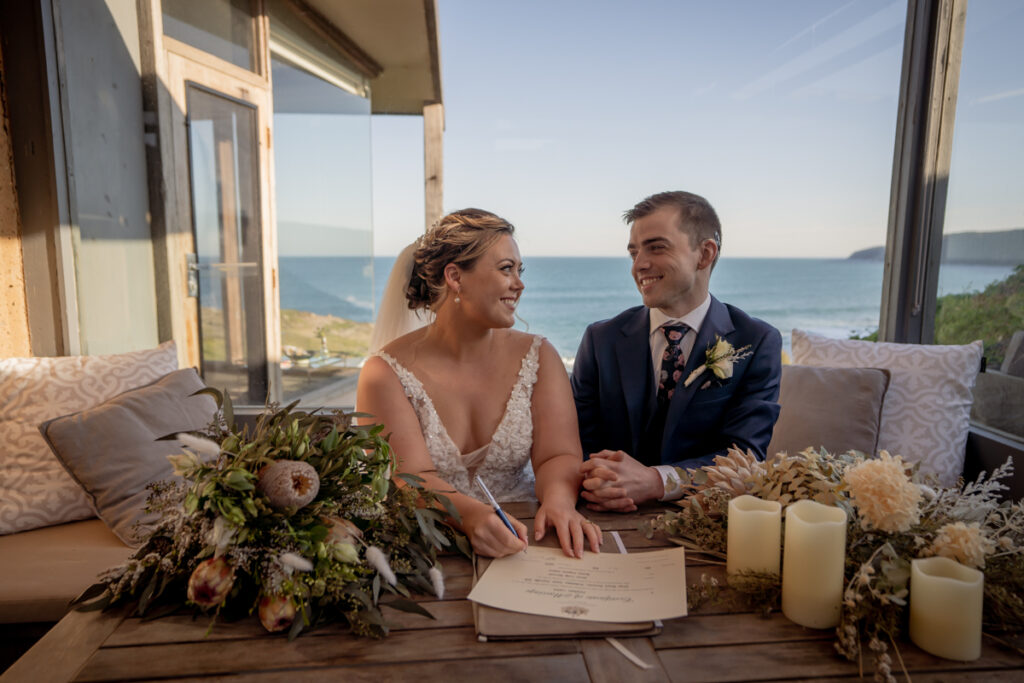 A wedding couple sitting together beside their bouquet and marriage register