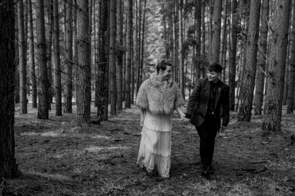 A wedding couple walking through a pine forest in black and white