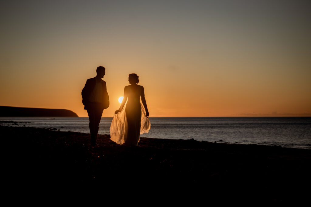 A wedding couple silhouetted on the beach at sunset