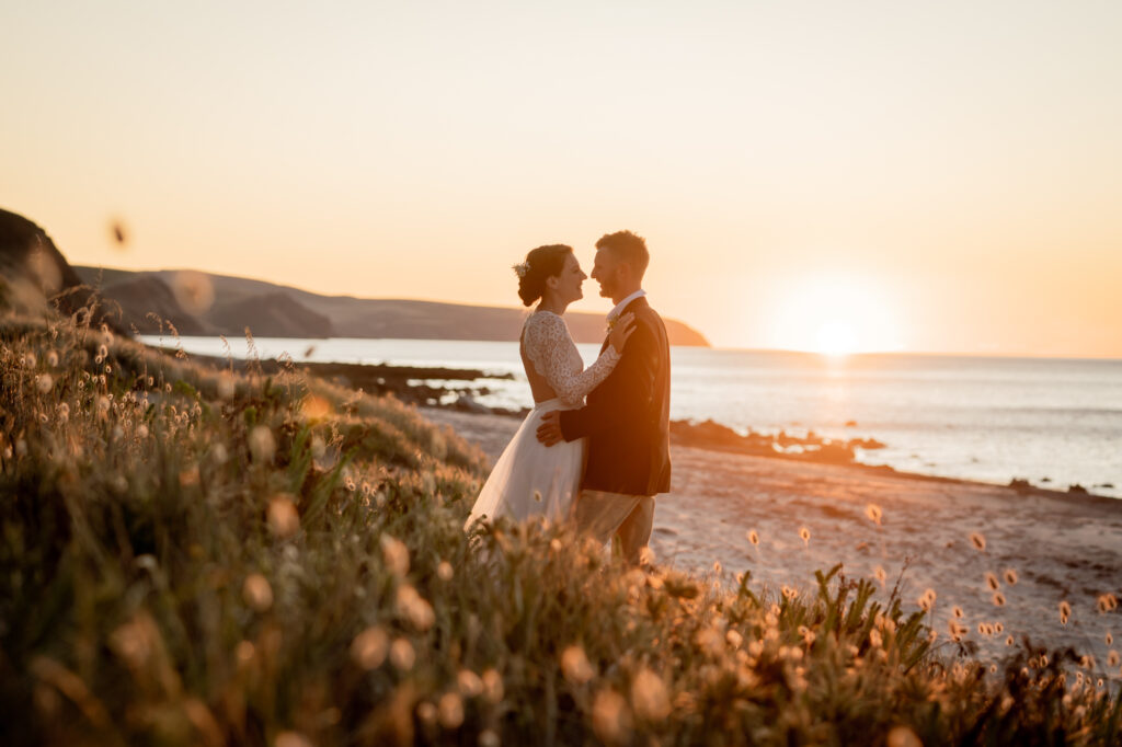 A wedding couple silhouetted against a coastal sunset