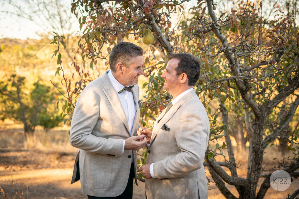 Two grooms together beneath autumn leaves