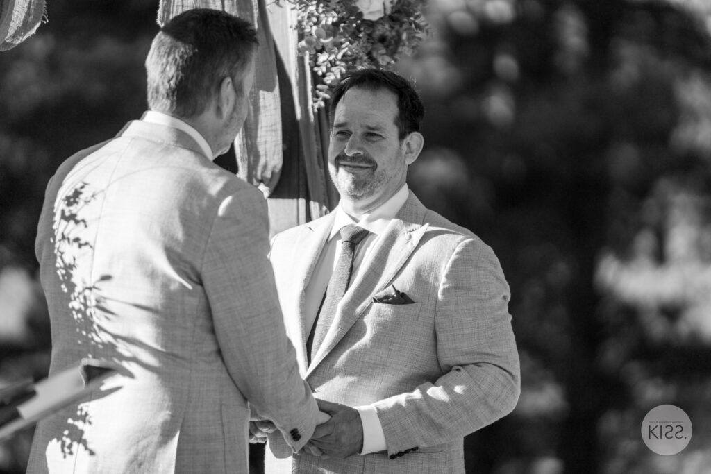 A groom smiling during his vows in black and white