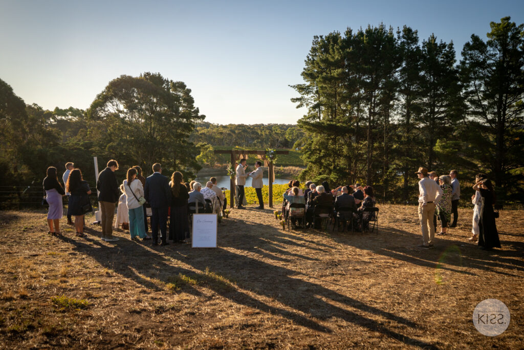 Guests gathered for an outdoor wedding ceremony in evening light