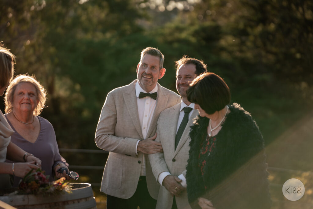 A groom and guests gathered beside a barrel outdoors