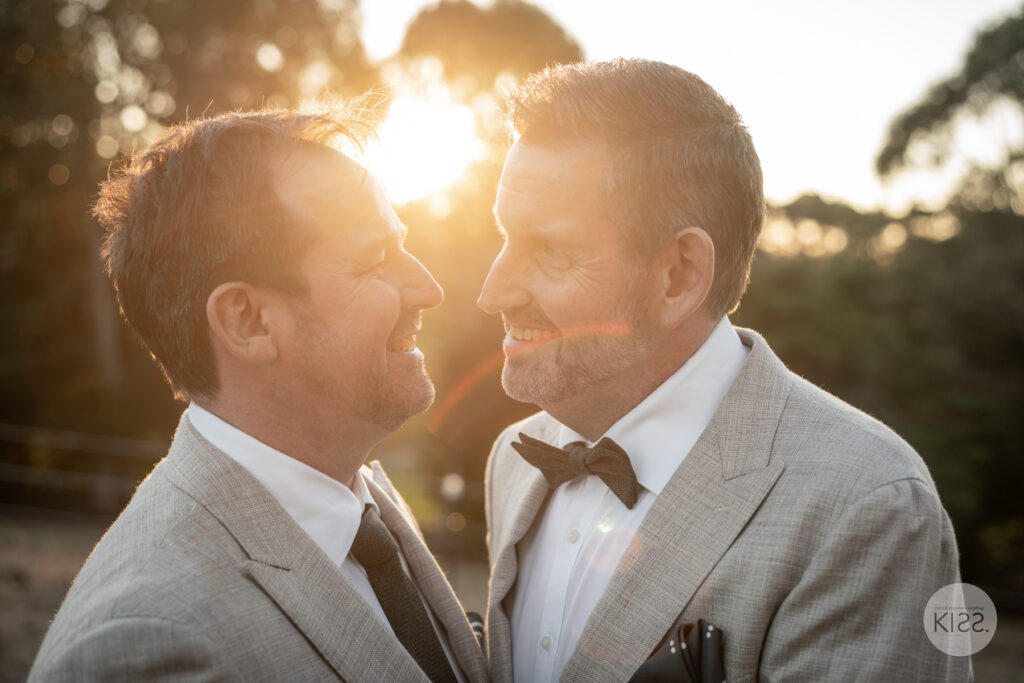 Two grooms smiling together in the evening sunlight